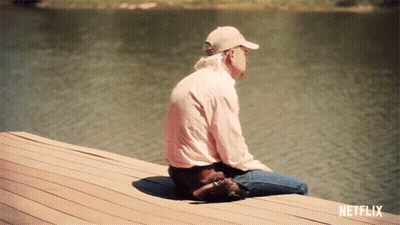 A Man Is Sitting On A Dock With A Netflix Logo Behind Him GIF