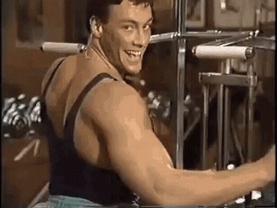 A Man Is Sitting On A Machine In A Gym And Smiling . GIF