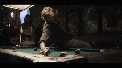A Man Is Sitting On A Pool Table With A Pool Cue GIF