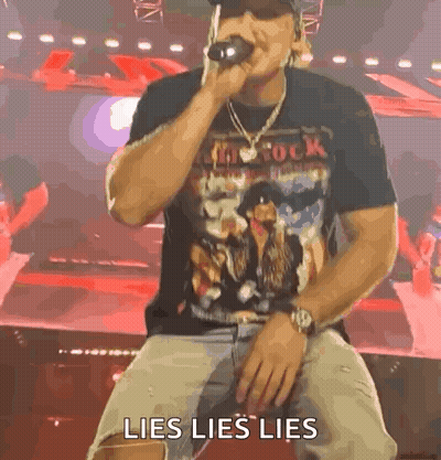 A Man Is Sitting On A Stage Singing Into A Microphone With The Words Lies Lies Lies Written On The Screen Behind Him . GIF
