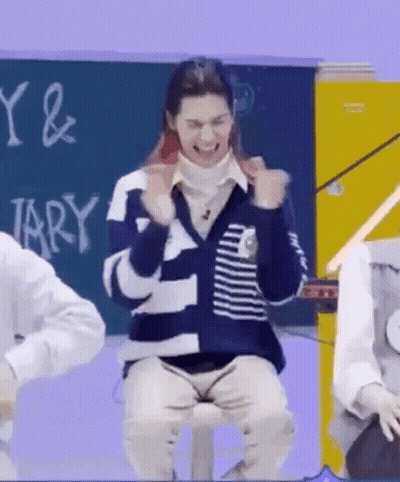 A Man Is Sitting On A Stool In Front Of A Blackboard In A Classroom And Making A Funny Face . GIF