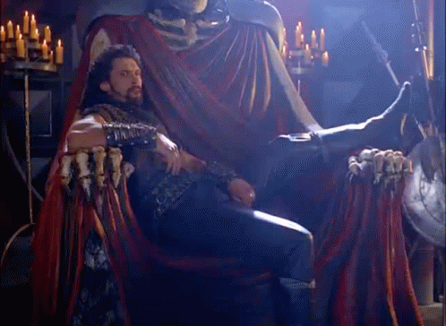 Man Sitting On Throne In Front Of Skeleton Statue GIF