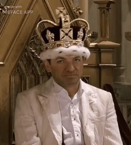A Man Is Sitting On A Throne Wearing A Crown And A White Suit . GIF