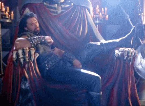 Man Sitting On Throne With Statue Behind GIF
