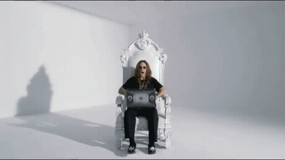 A Man Is Sitting On A White Throne Using A Laptop Computer . GIF