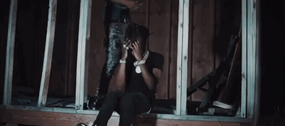 A Man Is Sitting On A Window Sill While Another Man Stands On Top Of A Building . GIF