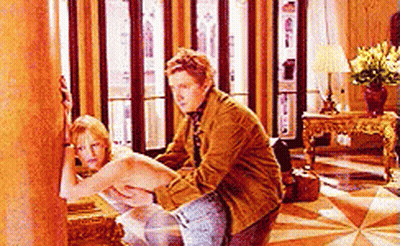A Man Is Sitting On A Woman 'S Lap In A Living Room . GIF