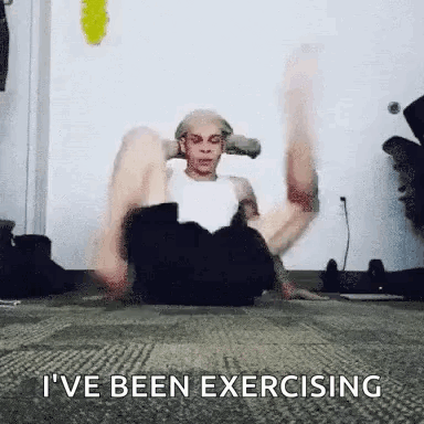 A Man Is Sitting On The Floor Doing Exercises With His Legs Up . GIF