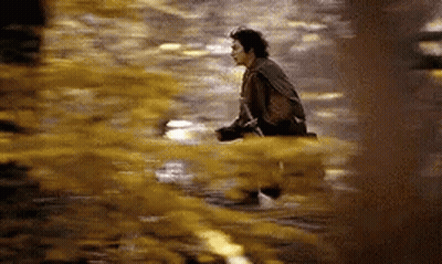 A Man Is Sitting On The Ground In A Puddle Of Water . GIF