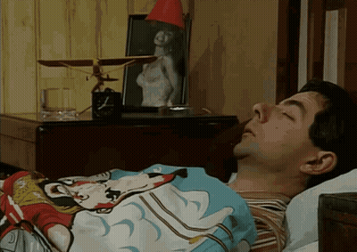 A Man Is Sleeping In A Bed With A Mickey Mouse Blanket On GIF