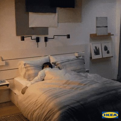 A Man Is Sleeping In A Bed With An Ikea Logo In The Background GIF