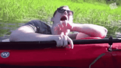 A Man Is Sleeping In A Red Kayak In The Water . GIF