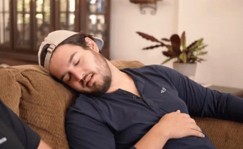 A Man Is Sleeping On A Couch And His Shirt Says Fox On It GIF