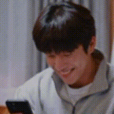 A Man Is Smiling And Looking At His Cell Phone . GIF