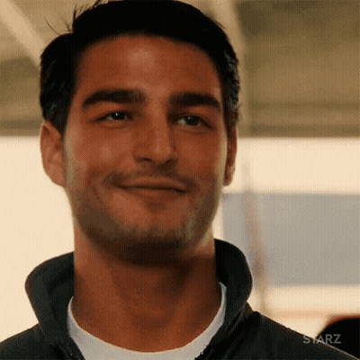 A Man Is Smiling And Looking At The Camera While Wearing A Black Jacket . GIF