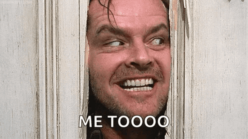 A Man Is Smiling And Looking Through A Hole In A Wall . GIF