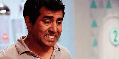 A Man Is Smiling And Making A Funny Face In Front Of A Wall With Triangles On It . GIF
