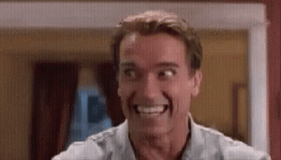A Man Is Smiling And Making A Funny Face While Standing In A Room . GIF