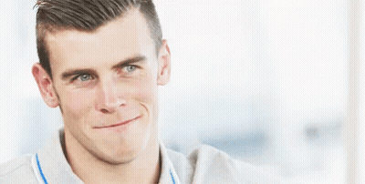 A Man Is Smiling And Making A Funny Face While Wearing A Grey Shirt . GIF