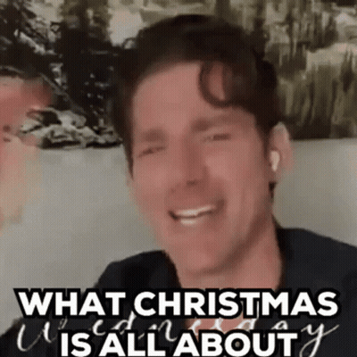 A Man Is Smiling And Saying `` What Christmas Is All About '' While Sitting On A Couch . GIF