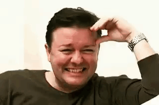A Man Is Smiling And Touching His Forehead . GIF