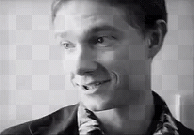 A Man Is Smiling In A Black And White Photo . GIF