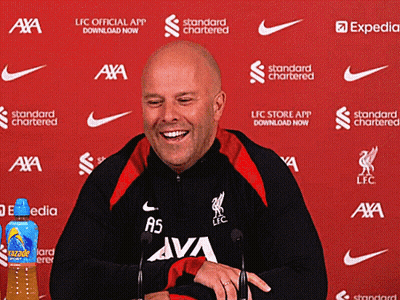 A Man Is Smiling In Front Of A Red Background That Says ' Standard Chartered ' GIF