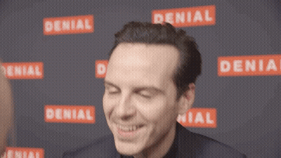 A Man Is Smiling In Front Of A Wall That Has Denial Written On It GIF