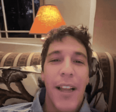 a man is smiling in front of an orange lamp
