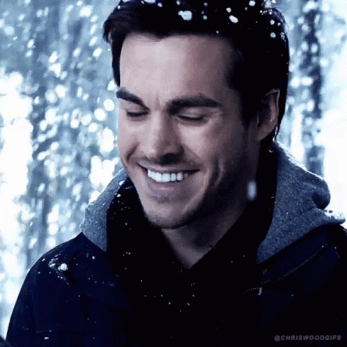 A Man Is Smiling In The Snow With His Eyes Closed GIF