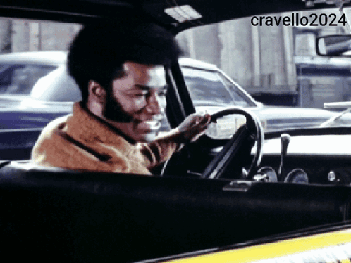 A Man Is Smiling While Driving A Car With The Hashtag Cravello2024 GIF