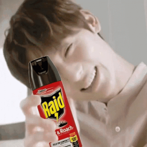 A Man Is Smiling While Holding A Bottle Of Raid Insect Spray GIF
