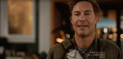 A Man Is Smiling While Holding A Purse In His Hand . GIF