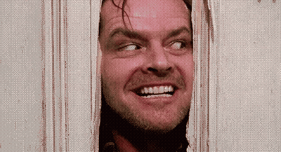 A Man Is Smiling While Looking Through A Door GIF