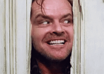 A Man Is Smiling While Looking Through A Doorway . GIF