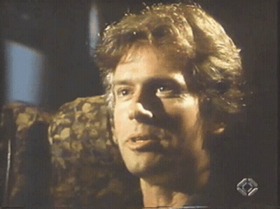 A Man Is Smiling While Sitting In A Chair On A Television Screen GIF