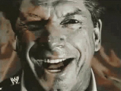 A Man Is Smiling With A Wrestling Logo On His Shirt GIF