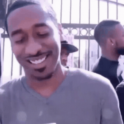 A Man Is Smiling With His Eyes Closed While Standing In Front Of A Crowd . GIF