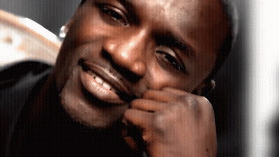 A Man Is Smiling With His Hand On His Face GIF