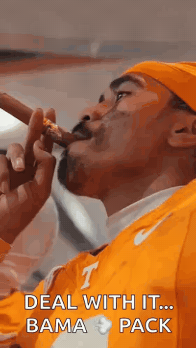 A Man Is Smoking A Cigar And Wearing An Orange Shirt . GIF