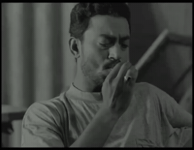 A Man Is Smoking A Cigarette In A Black And White Photo GIF