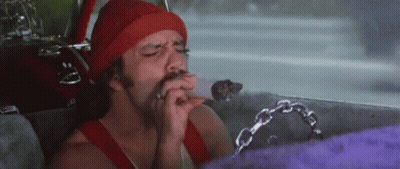 A Man Is Smoking A Cigarette In A Car While Wearing A Red Hat . GIF