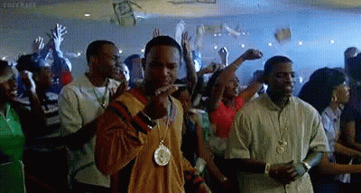 A Man Is Smoking A Cigarette In A Crowd Of People At A Party . GIF