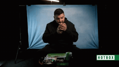 A Man Is Smoking A Cigarette In Front Of A Hotbox Banner GIF