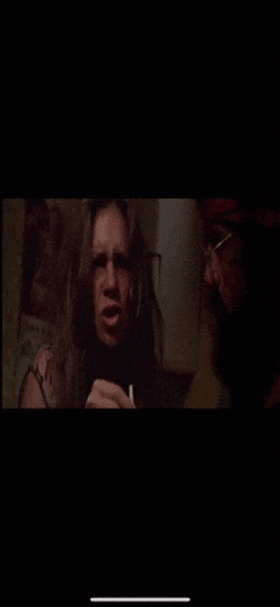 A Man Is Smoking A Cigarette Next To A Woman Who Is Making A Face . GIF