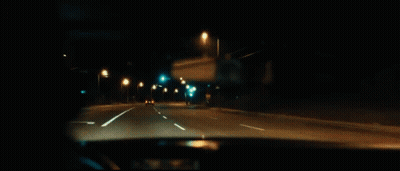 A Man Is Smoking A Cigarette While Driving A Car At Night . GIF