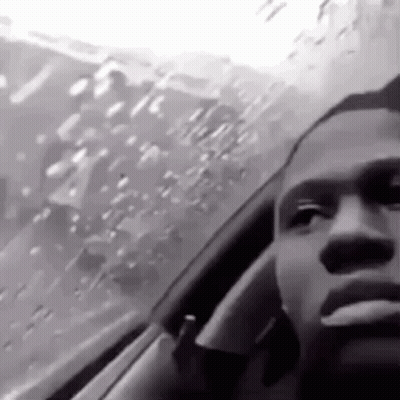 A Man Is Smoking A Cigarette While Driving A Car In The Rain . GIF