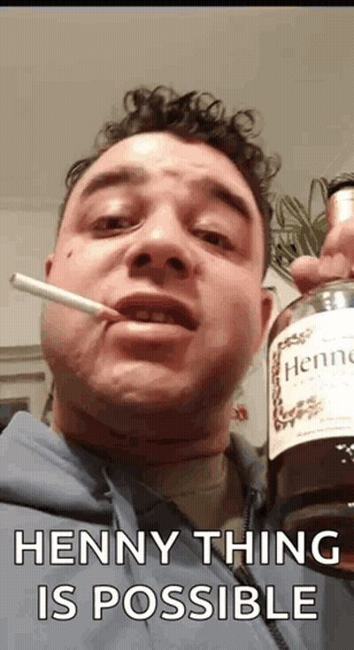 A Man Is Smoking A Cigarette While Holding A Bottle Of Hennessy Cognac . GIF