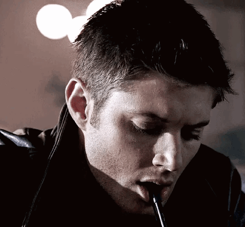 A Man Is Smoking A Cigarette With A Straw In His Mouth . GIF