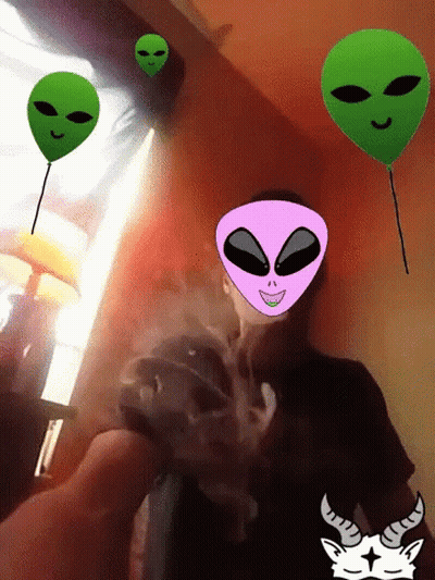 A Man Is Smoking A Cigarette With Alien Faces On His Face GIF
